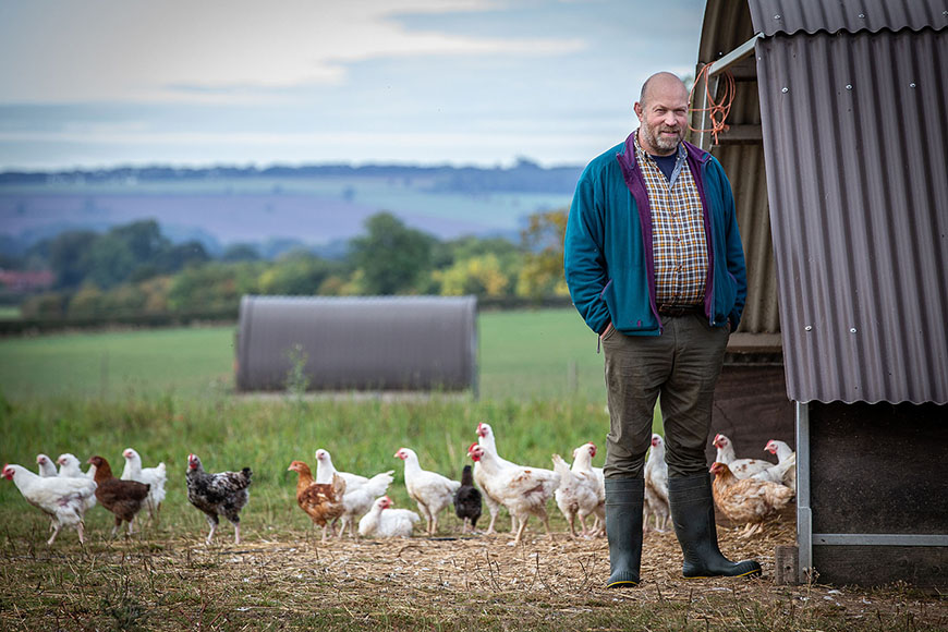 Farmer stood beside chicken coup outside by Polly Baldwin Farmer stood beside chicken coup outside by Polly Baldwin