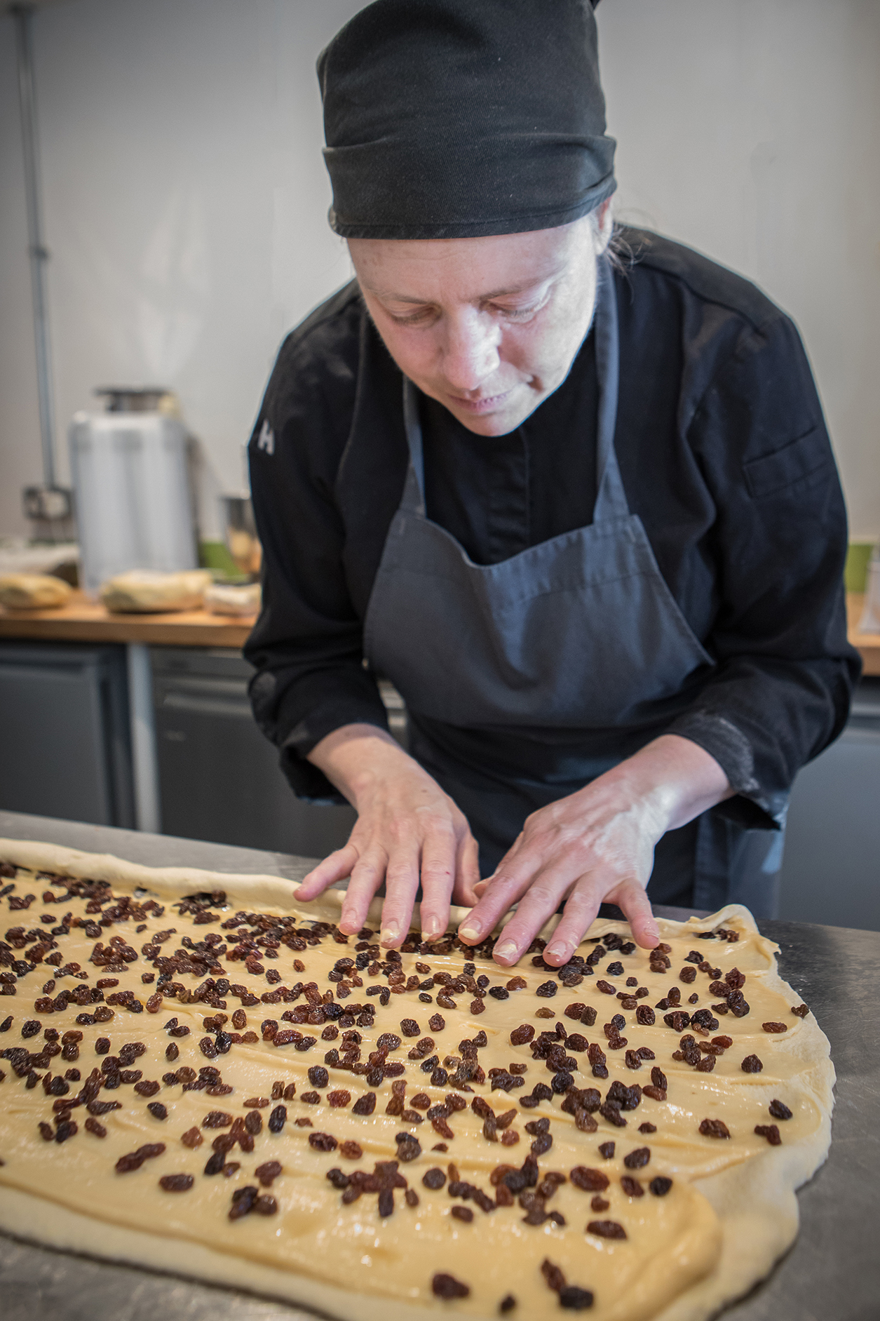 Emma spreading raisins onto dough by Polly Baldwin