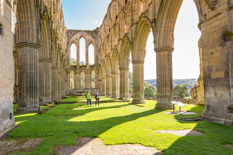 Two women among the ruins of a stone abbey. Credit Visit Britain / Gary Walsh.