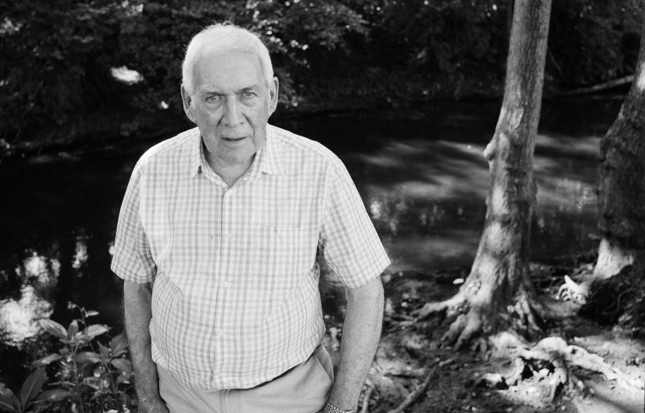 Black and white photo of a man near a river.