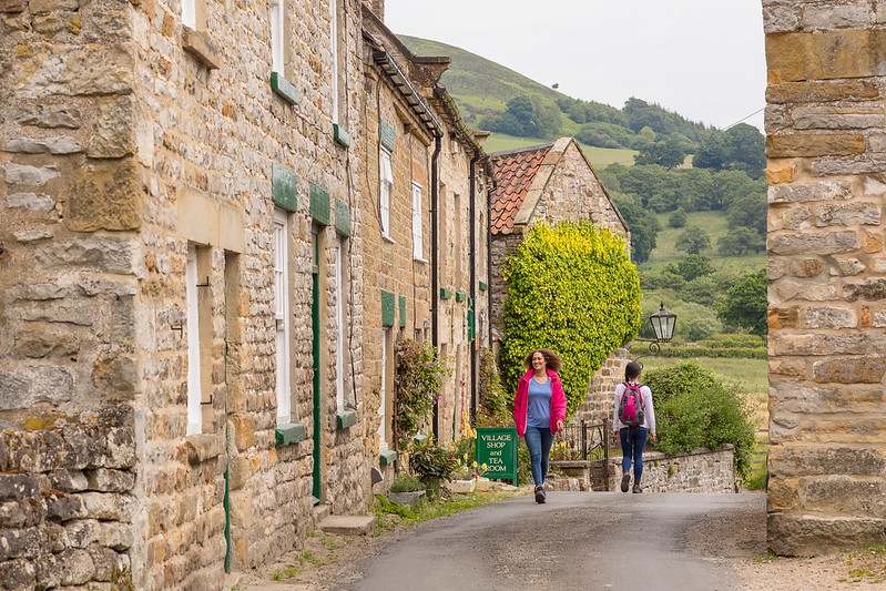 Two women walking between traditional stone building. Credit Dependable Productions.
