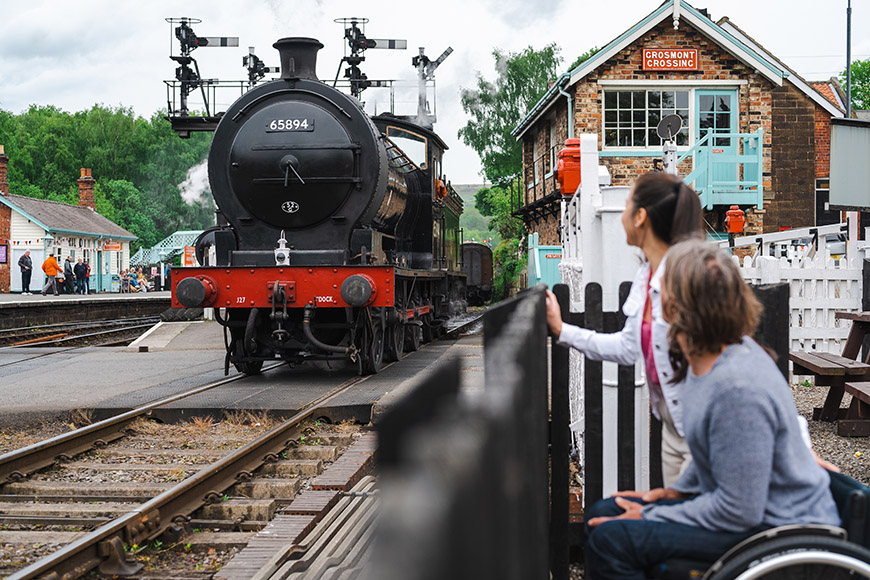 Man in wheelchair watching the steam train Grosmont station (c) VisitBritain/Peter Kindersley