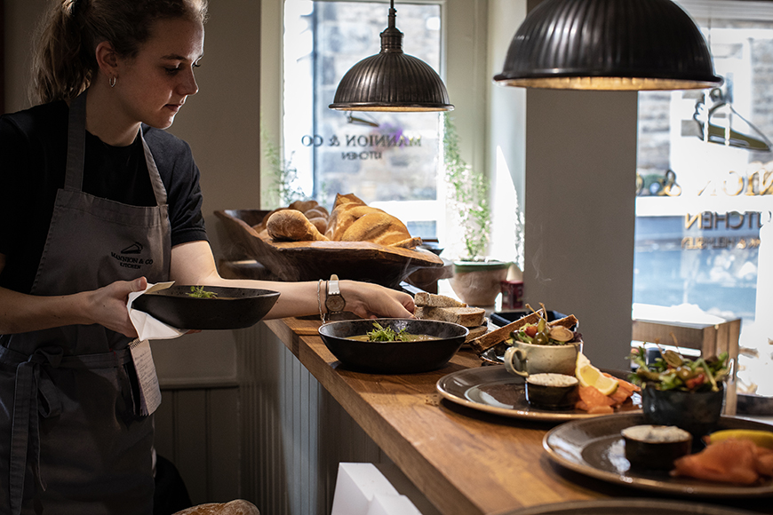 Girl collecting food from counter by Polly Baldwin