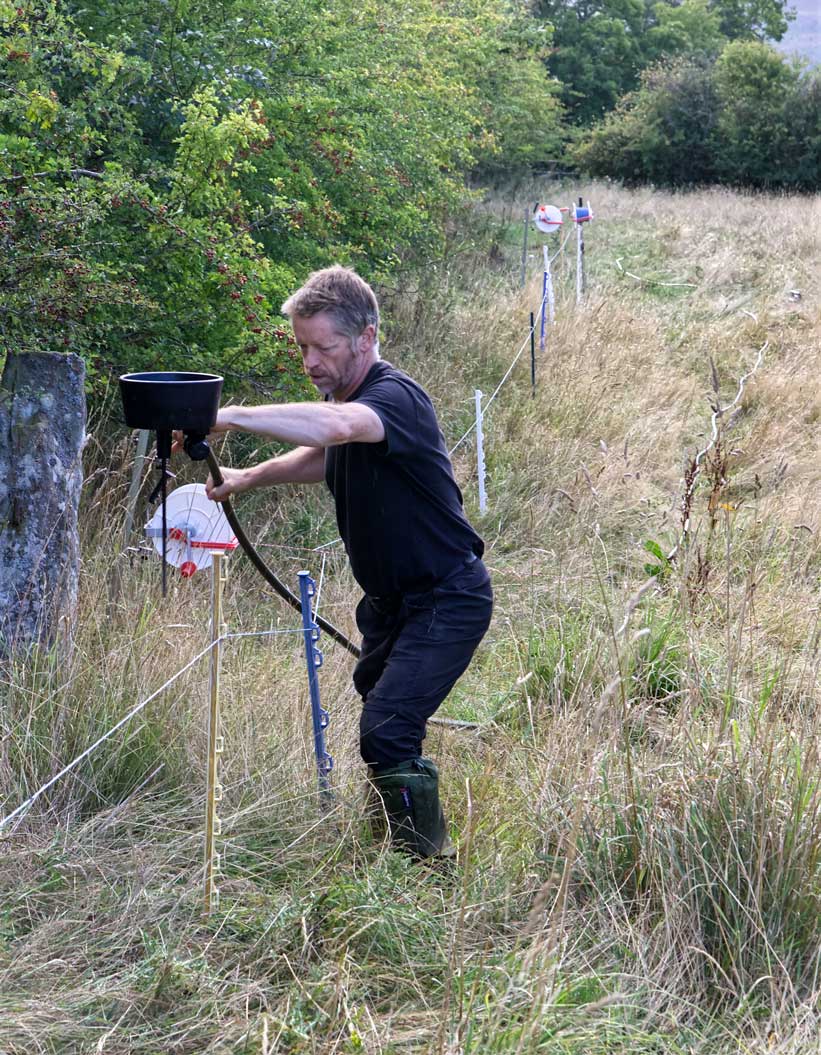 Man working on a portable trough in a field.