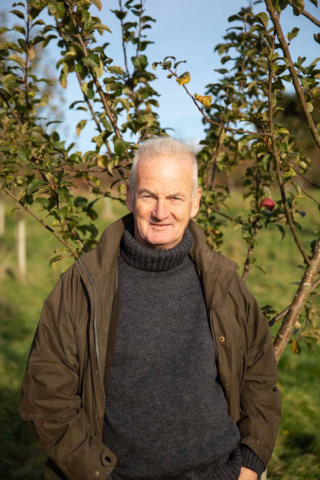 Male stood in front of an apple tree among an orchard. Credit Charlie Fox.