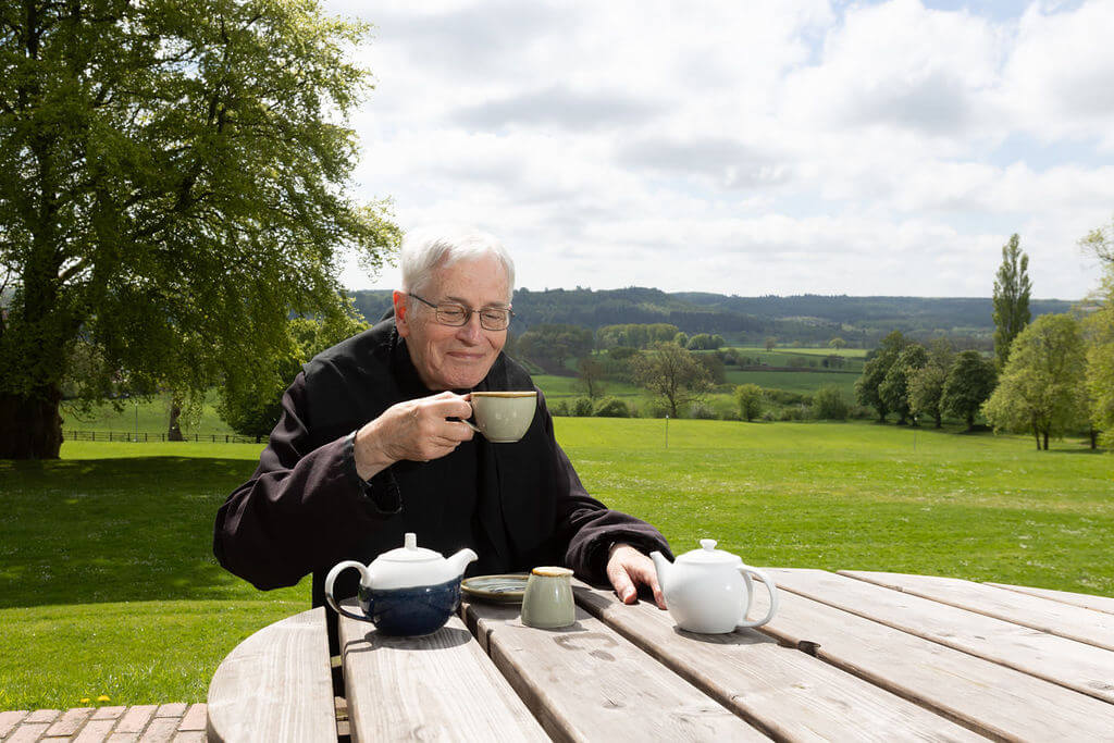 A monk at Ampleforth Abbey enjoying a cup of tea with a view.