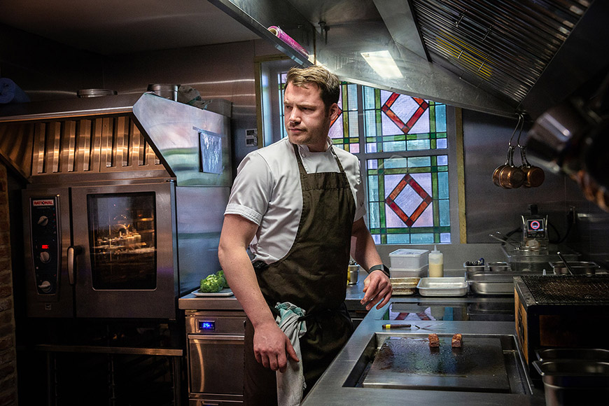 Chef Tommy Banks standing over stove in the kitchen by Polly Baldwin Chef Tommy Banks standing over stove in the kitchen by Polly Baldwin