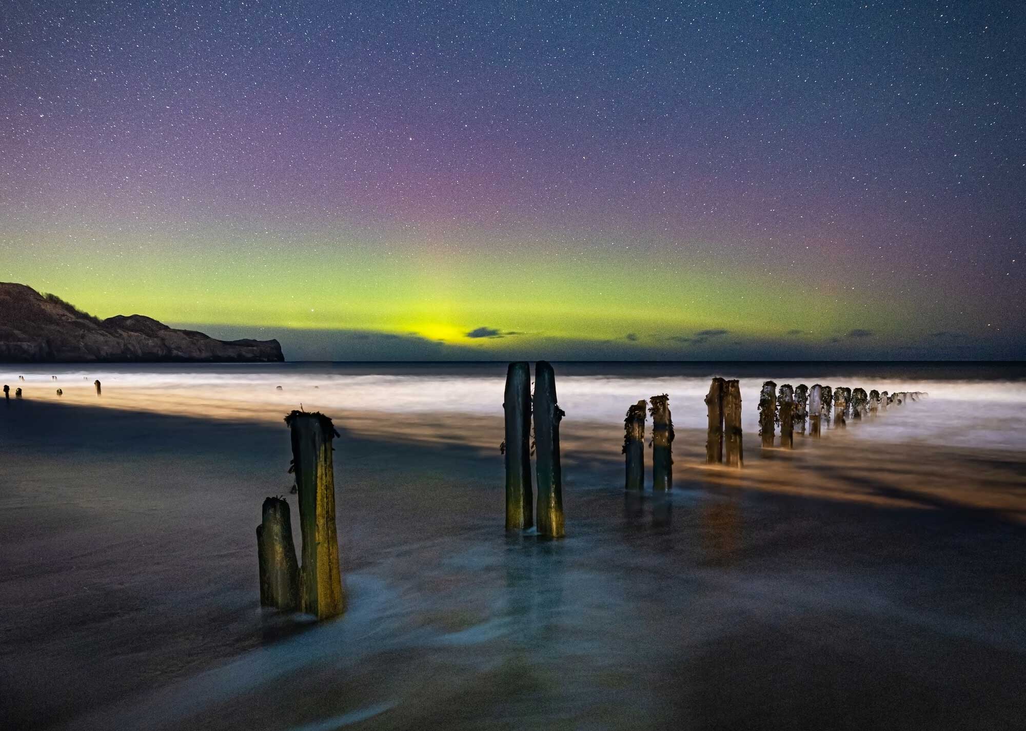 Aurora Borealis above the sea and rugged coastline. Credit Steve Bell.