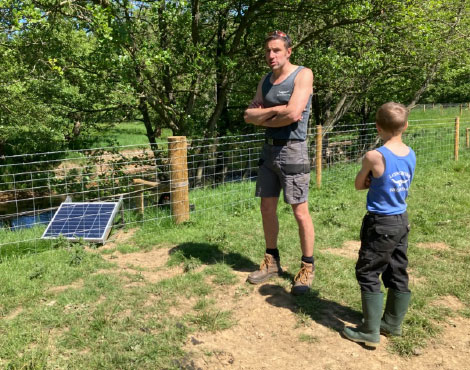 Man and young child stood next to a water pump near a river. Man and young child stood next to a water pump near a river.