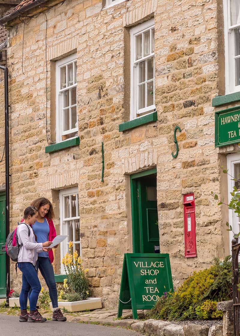 Two people looking at a map outside a stone building. Credit Dependable Productions.