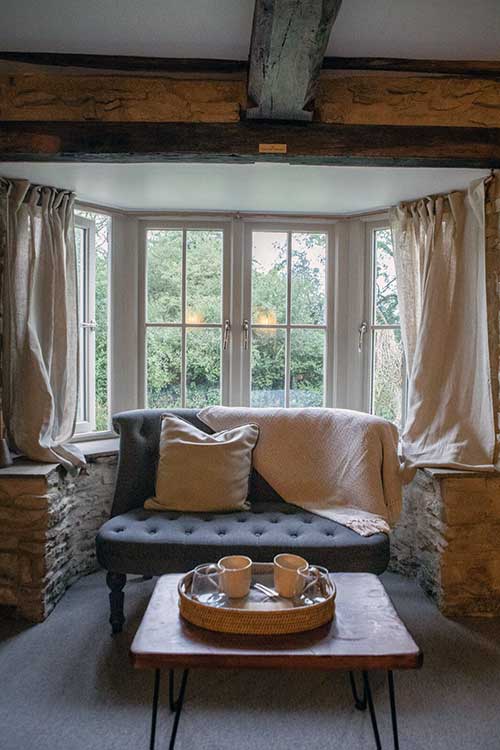 Sofa in front of a bay window with coffee cups on table