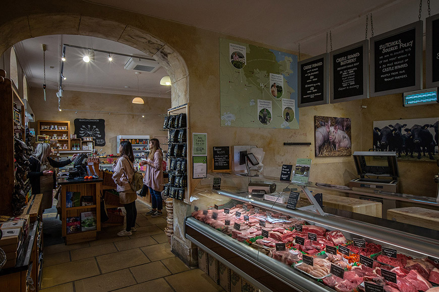 Inside farm shop- meat counter and customers talking to staff by Polly Baldwin