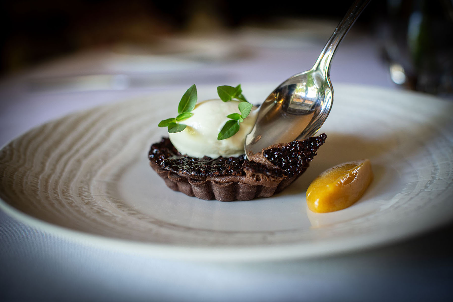 Chocolate tart with a spoon cutting into it by Polly Baldwin