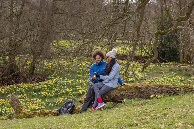 Man and woman sat down on a tree log enjoying a hot drink from a flask in Farndale (c) Dependable Productions