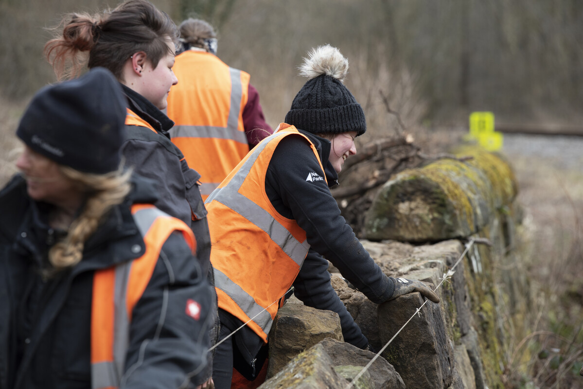 People repairing a dry stone wall near a railway line. Credit Anglo American.