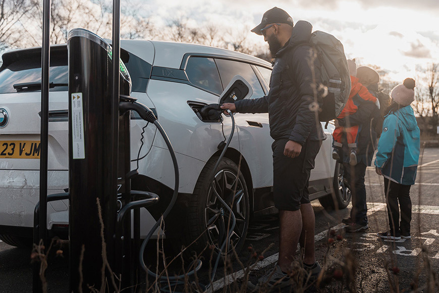 Haroon Mota plugging in a BMW car at an EV charger at Sutton Bank National Park Centre (c) BMW UK