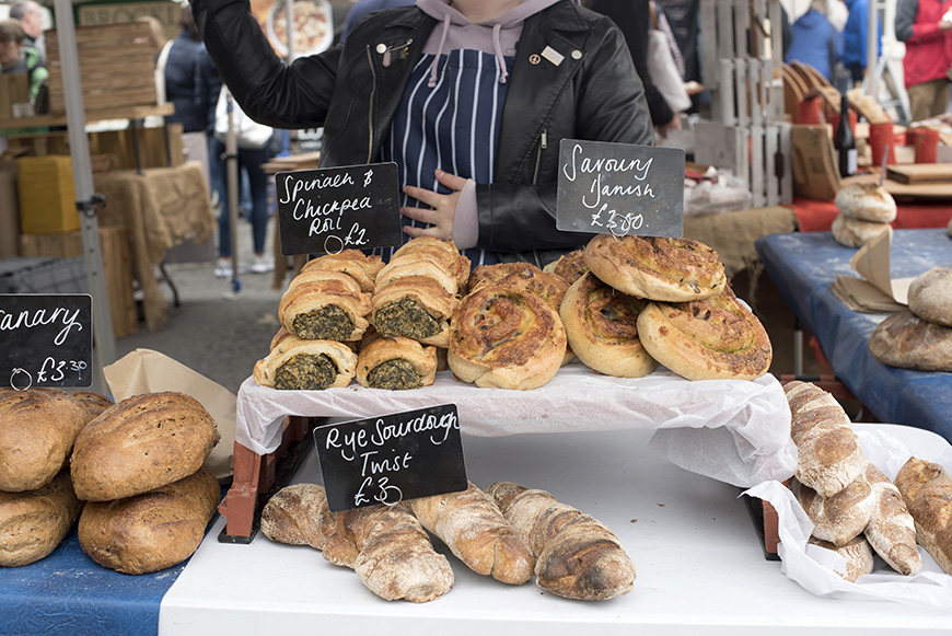 A market stall at Malton Food Festival with a display of bread and other baked goods © VisitBritain/Melody Thornton