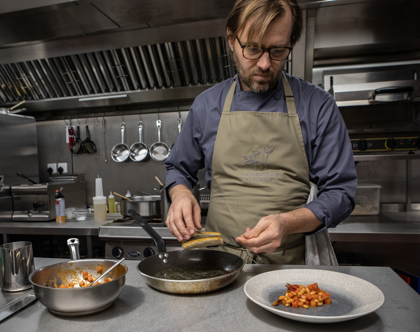 Peter in the kitchen serving seabass dish by Polly Baldwin Peter in the kitchen serving seabass dish by Polly Baldwin