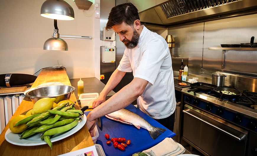 Chef Jason preparing food in kitchen by Ceri Oakes