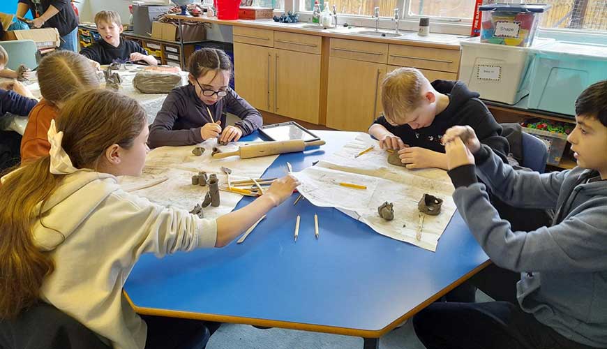 children sat at a table making clay habitats