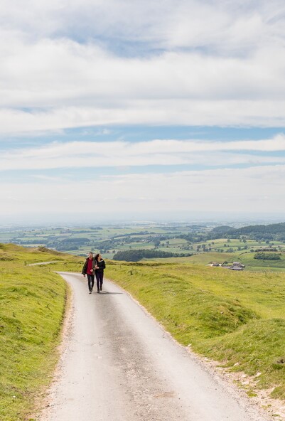 Two walkers on road surrounded by views by Dependable Productions