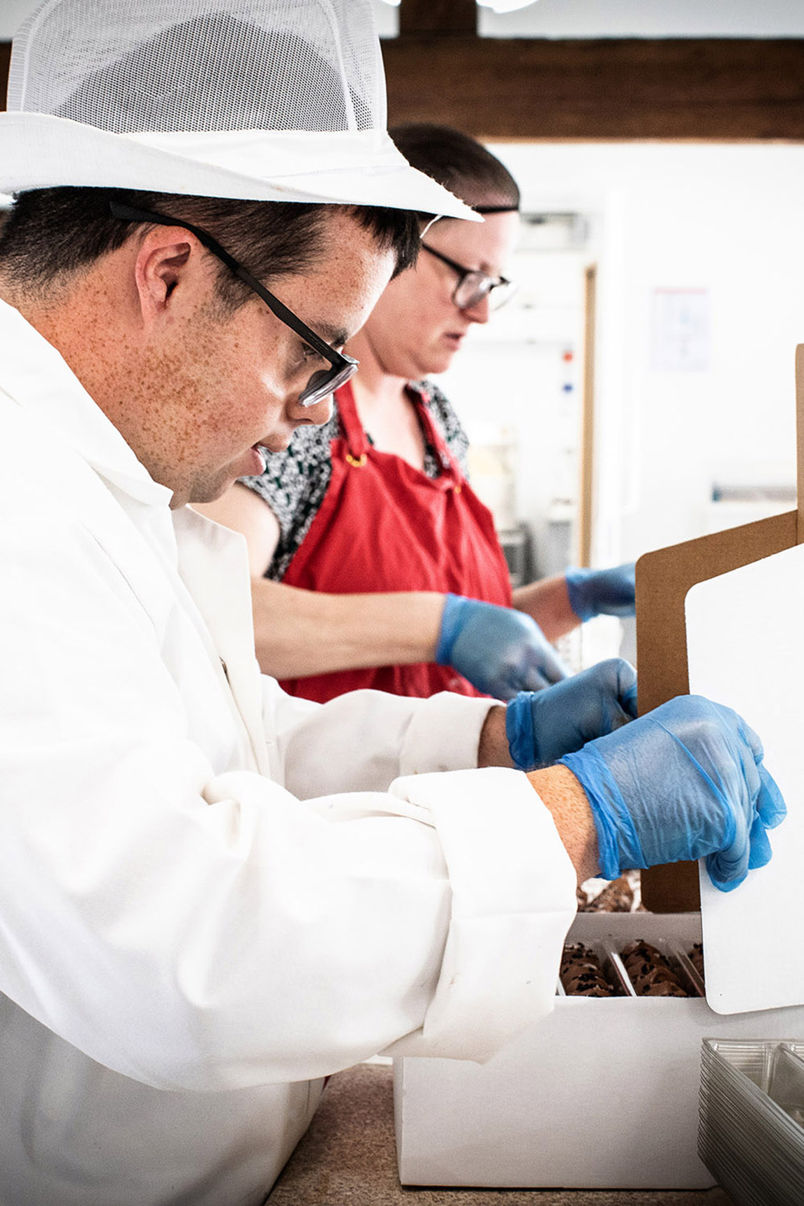 Young man and female co-worker packaging chocolates by Polly Baldwin Young man and female co-worker packaging chocolates by Polly Baldwin