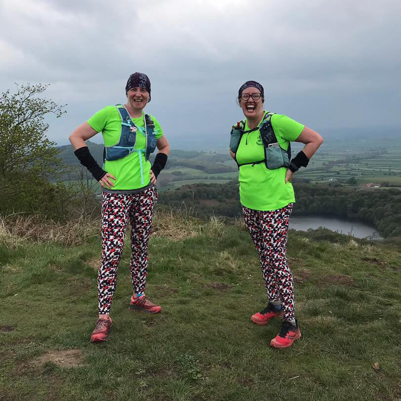 Two women in running gear standing above Lake Gormire
