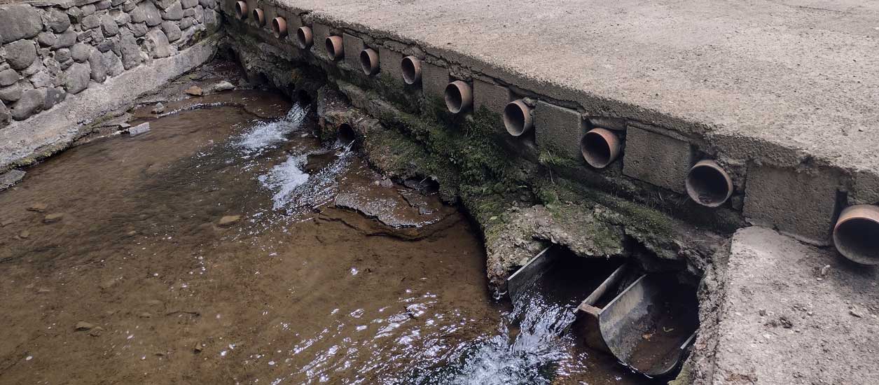 Pipes embedded into concrete. River water is flowing through them.
