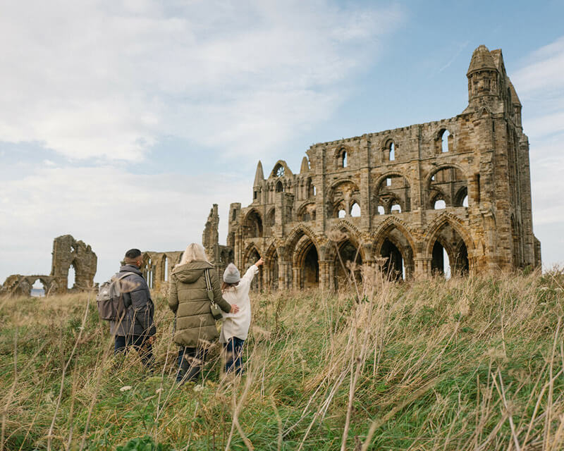 Family walking towards Whitby Abbey. Credit: Orillo.