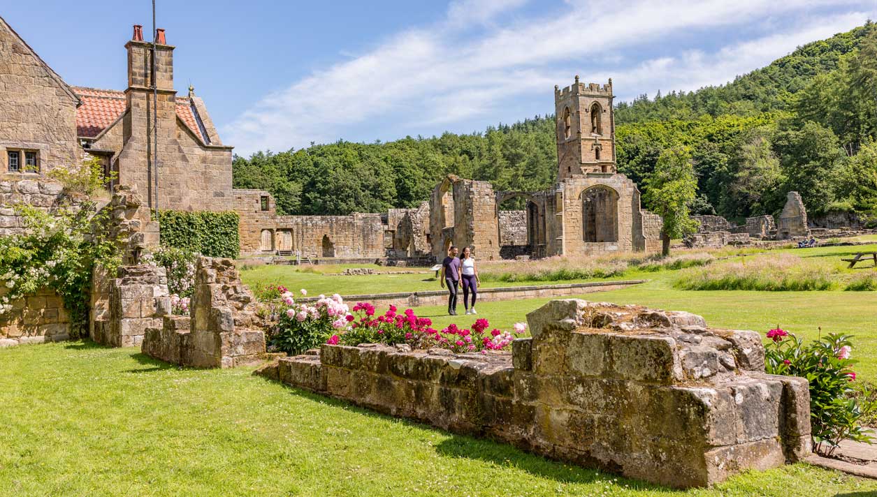 Two people walking among the ruins of Mount Grace Priory. Credit Dependable Productions.
