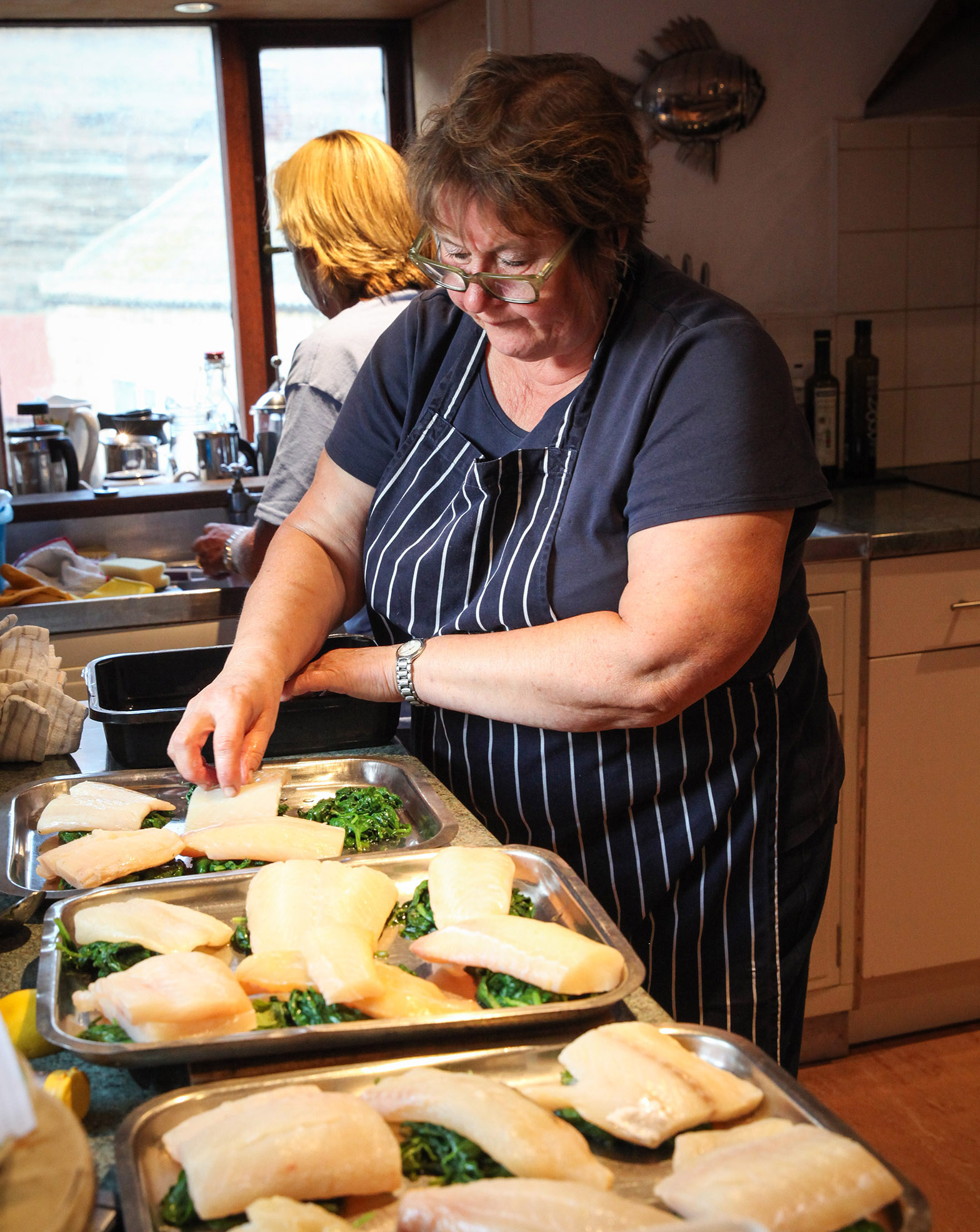 Lisa preparing fish in the kitchen by Ceri Oakes