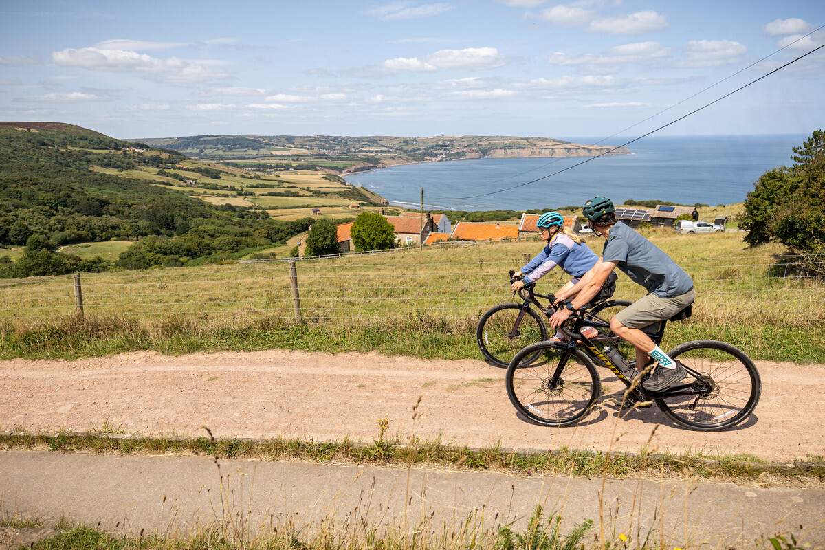 Leisure cyclists riding gravel bikes above Robin Hood's Bay on the Cinder Track 