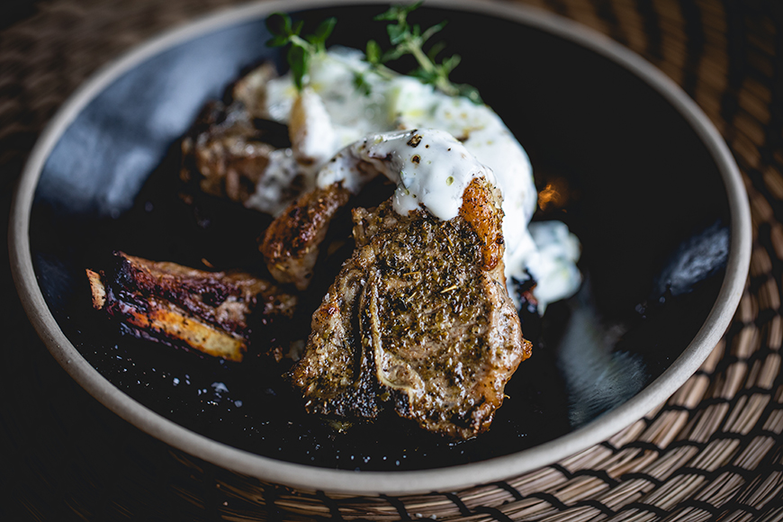 Lamb chops drizzled with tzatziki served on a plate 
