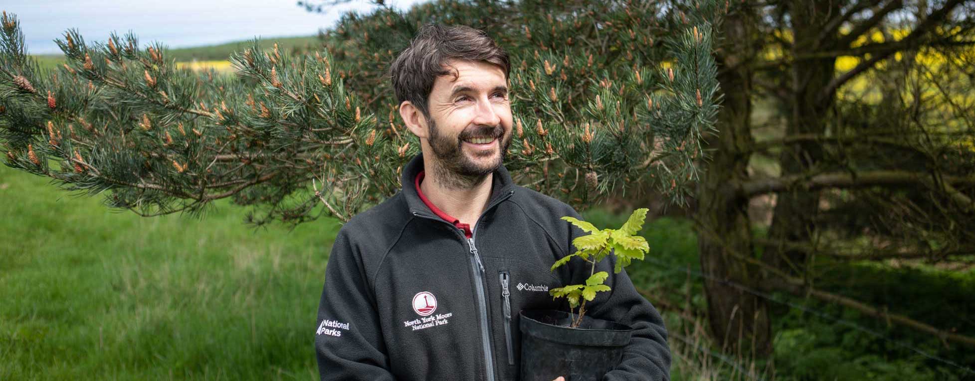 Man holding an oak sapling. Credit Charlie Fox. Man holding an oak sapling. Credit Charlie Fox.