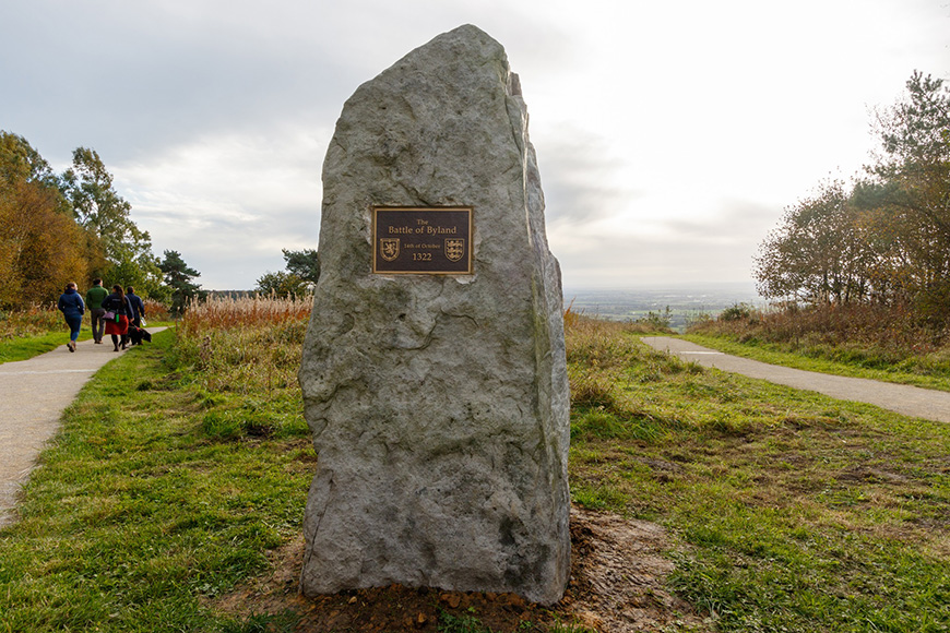 A large stone monument commemorating the Battle of Byland, located in a patch of grass with a cloudy sky behind. 