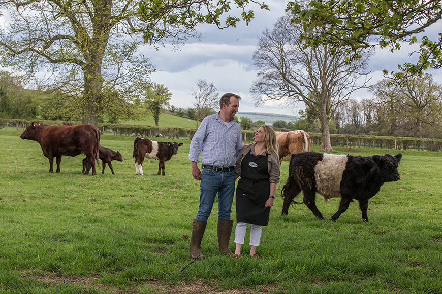 Richard and Lucy stood in the field with cattle by Polly Baldwin