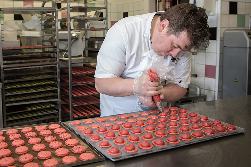 Florian piping ganache into macarons in the kitchen by Polly Baldwin