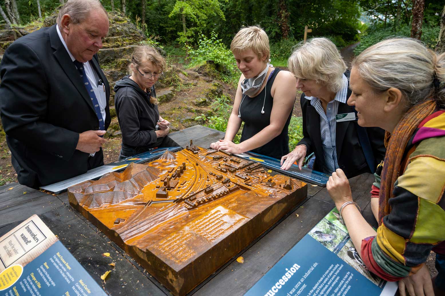 Photo of people looking at a cast model among a woodland in Grosmont.