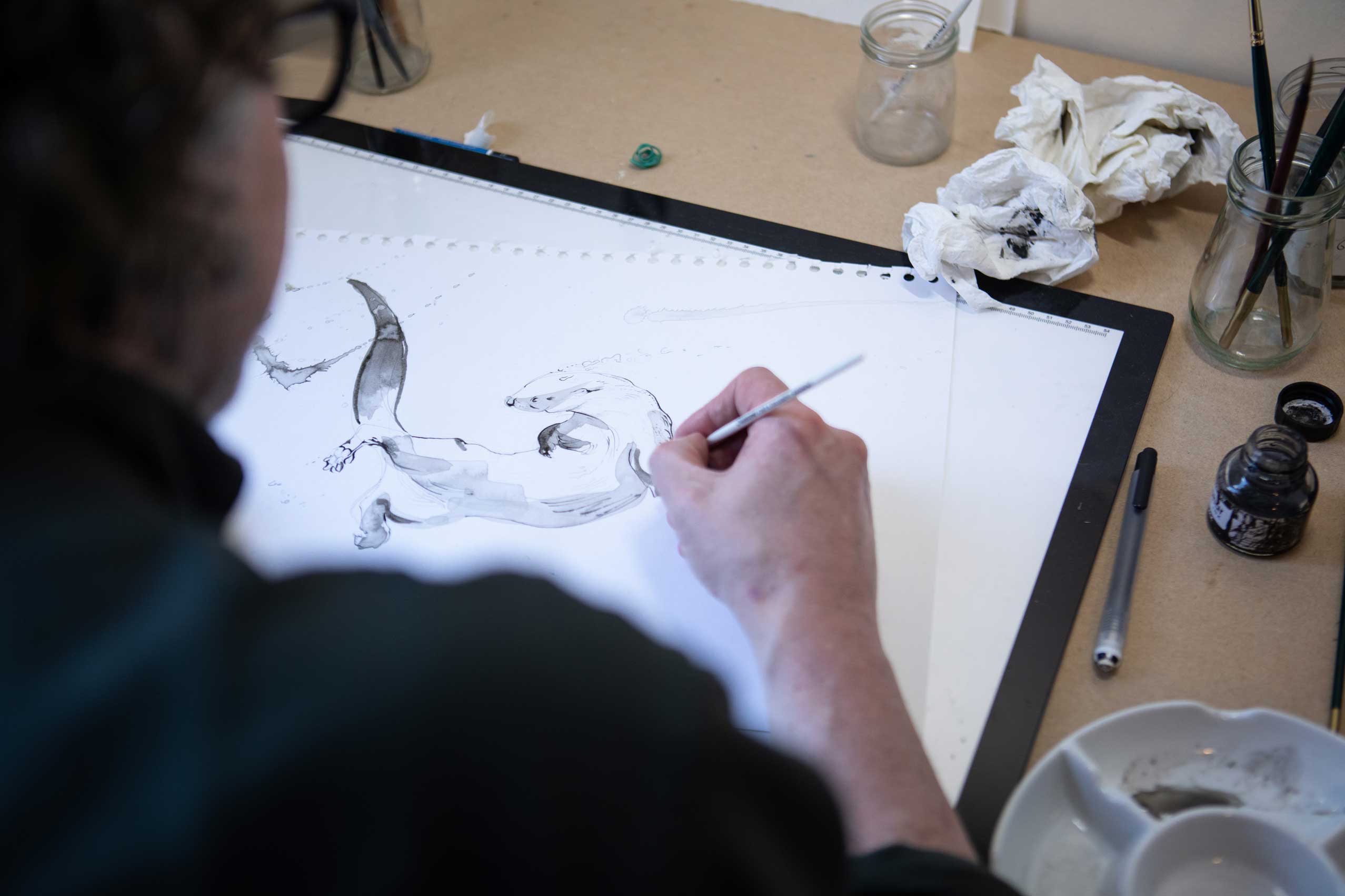 Photo of Nick Ellwood drawing an otter using ink. Credit Charlie Fox.