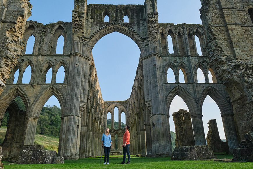 Man and woman at Rievaulx Abbey, woman is using a walking stick Credit VisitBritain Images/Daniel Wildey