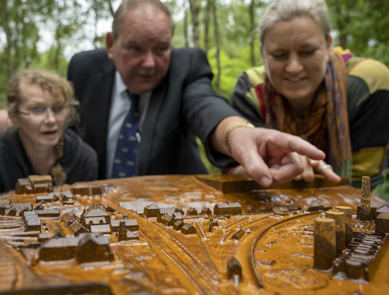 Close up of people looking at a cast model among a woodland in Grosmont.
