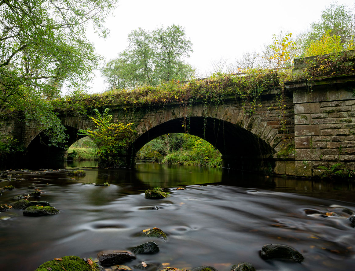 Photo of river flowing between an old stone bridge