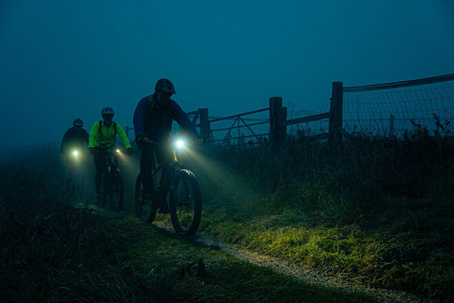 Three cyclists riding at night at Sutton Bank for the Dark Skies Gravel Bike Ride. Photo taken by Hewitt and Walker.