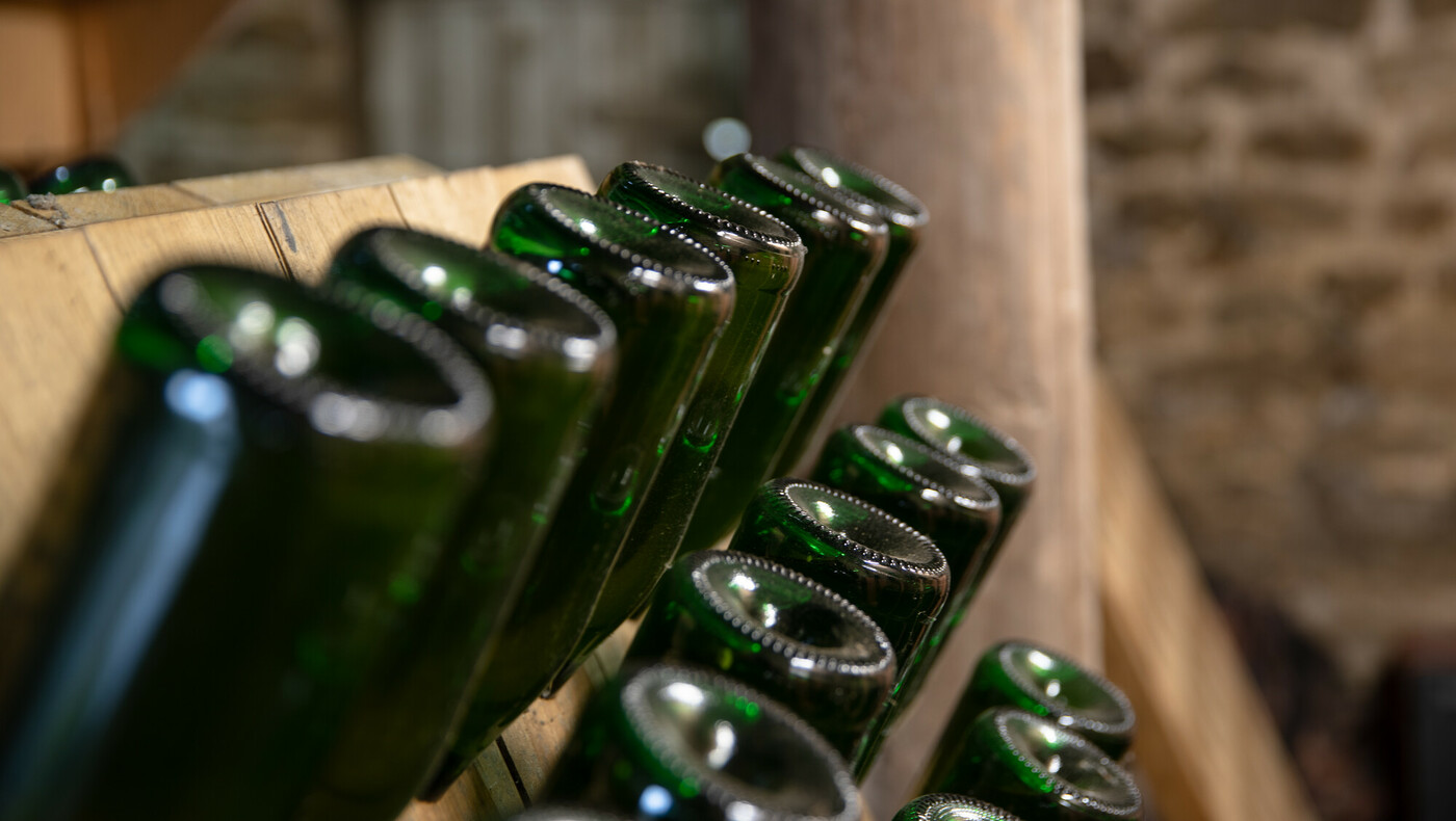 Close up of cider bottles in a large wooden rack. Credit Charlie Fox.